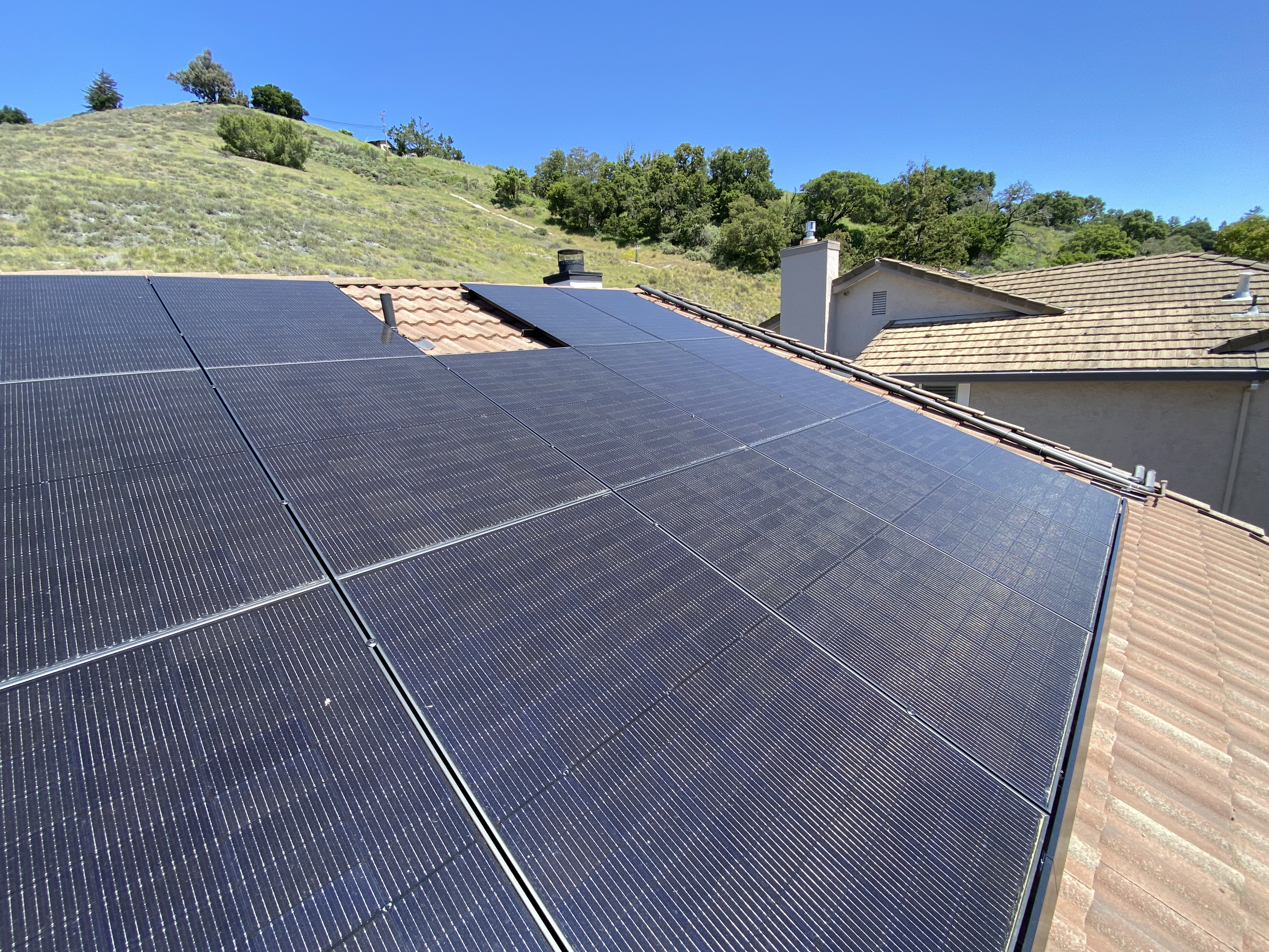 Rooftop view of the 21kW solar array on a tile roof with hillside backdrop