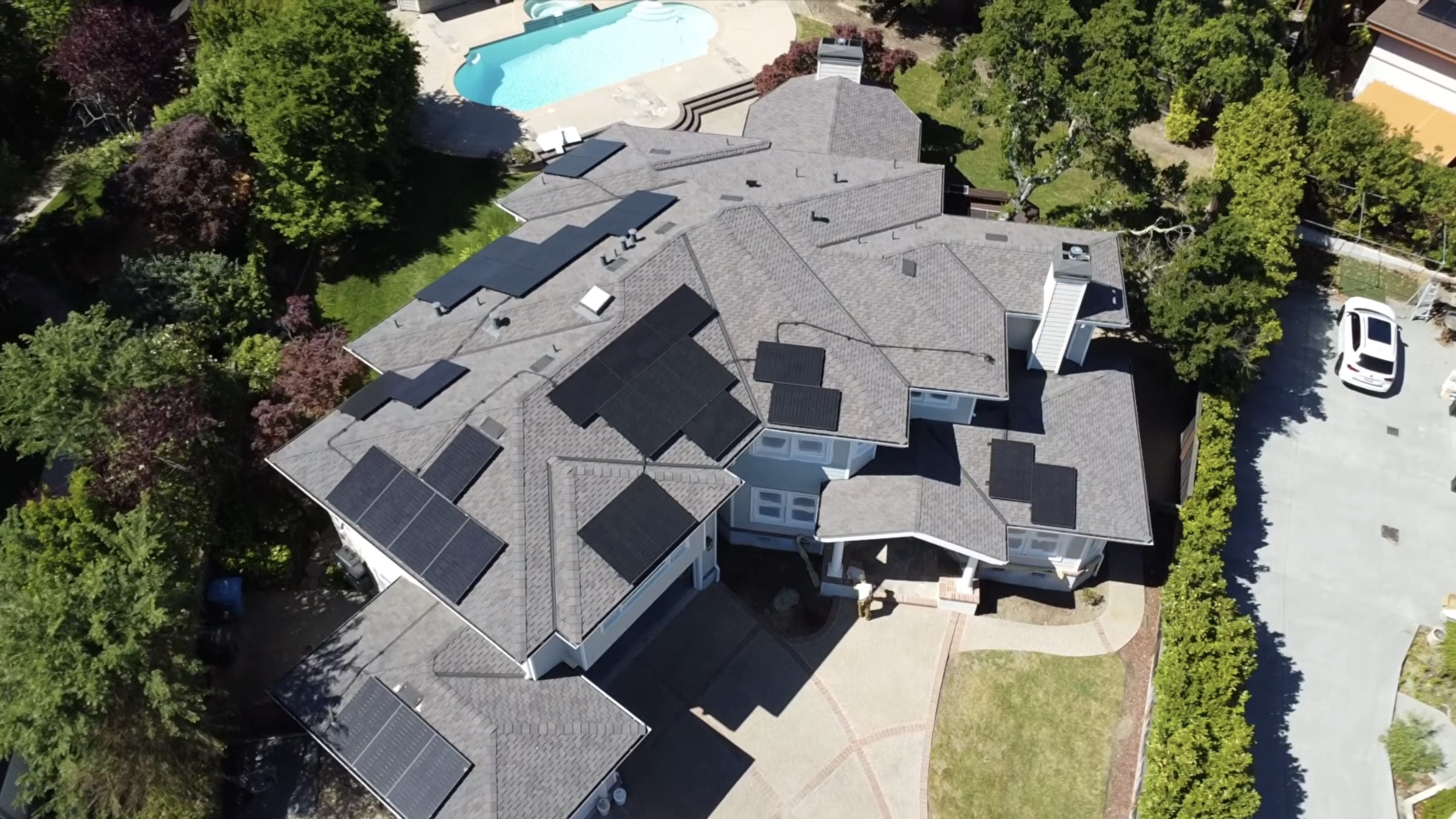 Aerial view of a large multi-facet roof with solar panels across many roof planes